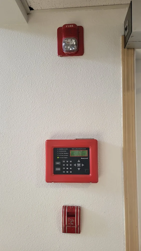 Wall-mounted fire alarm annunciator with a horn strobe and manual call point.